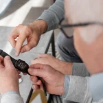 older man examining a wearable medical alert device displaying health data