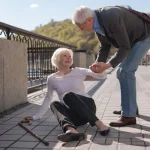 senior man helping fallen senior woman on the road